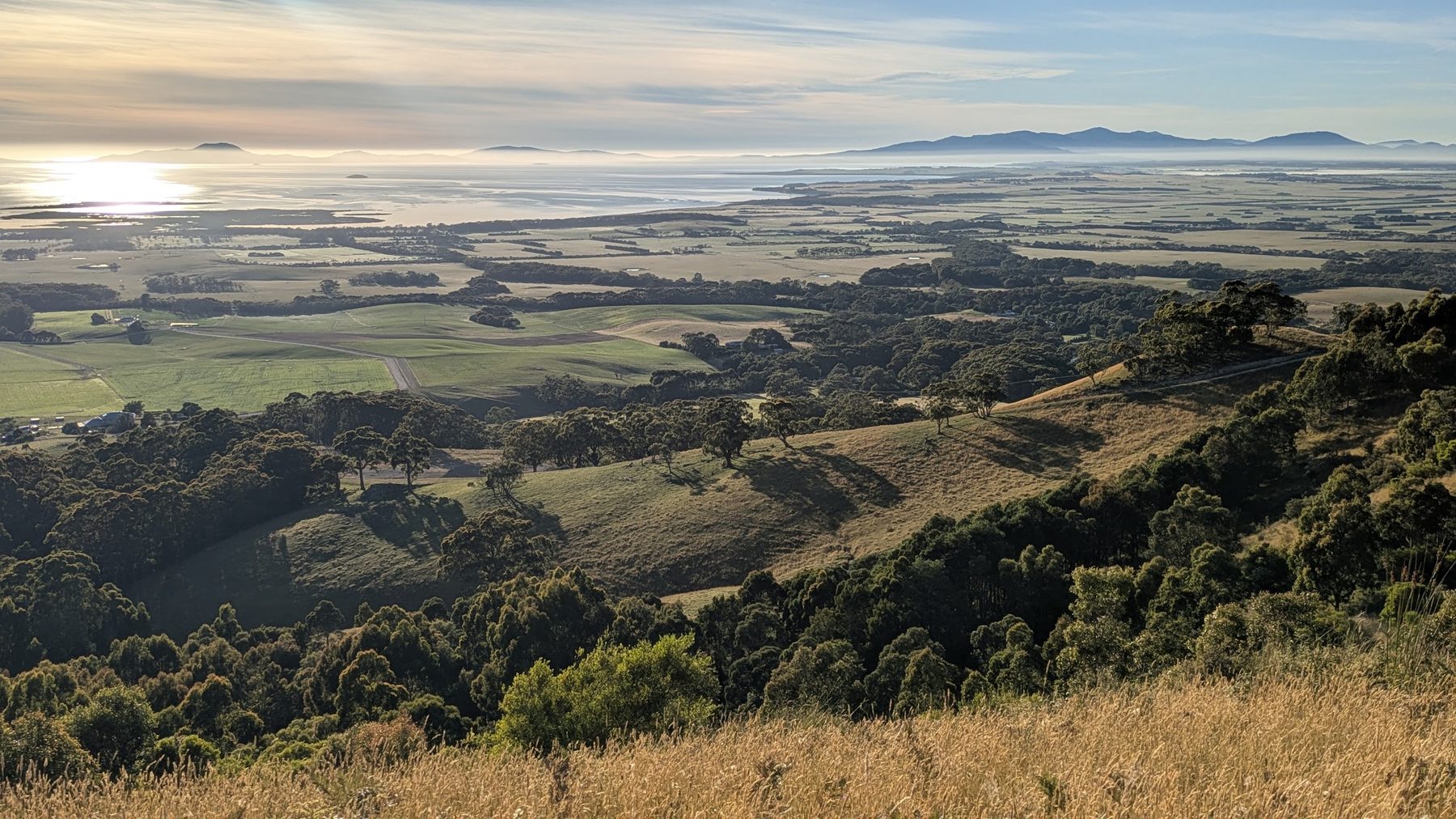 Looking south from the Hoddle Range over farmland and bush to Corner Inlet and the Wilsons Promontory ranges in early light.